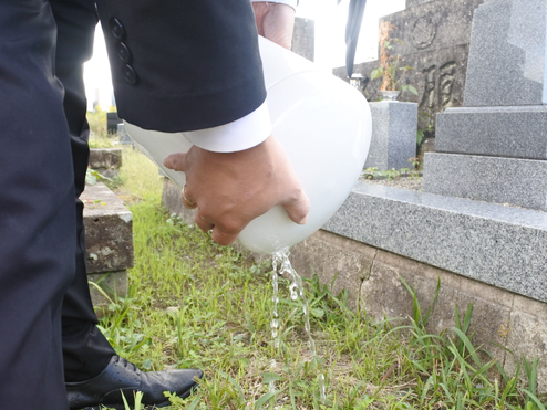 水が溜まった一般的な骨壷から水を抜いている様子。