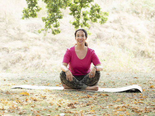 Bild von Anja, wie sie im Schlosspark auf ihrer Yogamatte sitzt und die Natur geniesst. Entspannung, zu sich selbst kommen und finden, die Ruhe geniessen und dem Stress entgehen.
