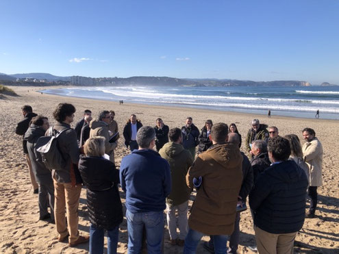 Menschen stehen an einem Strand im Kreis und erörtern die Situation zur Klimaanpassung