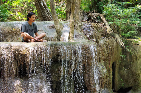 Un homme se détend au bord d'une cascade du parc d'Erawan en Thaïlande