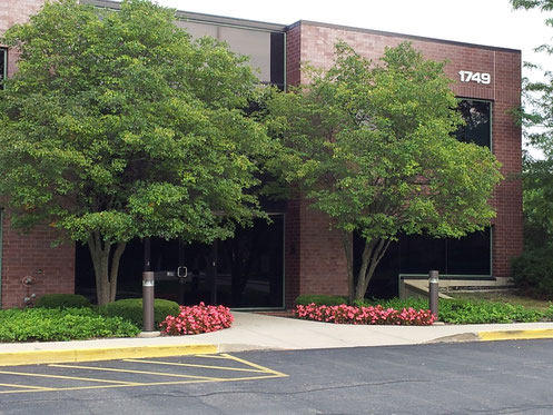 Two-story brick building with trees and flowers