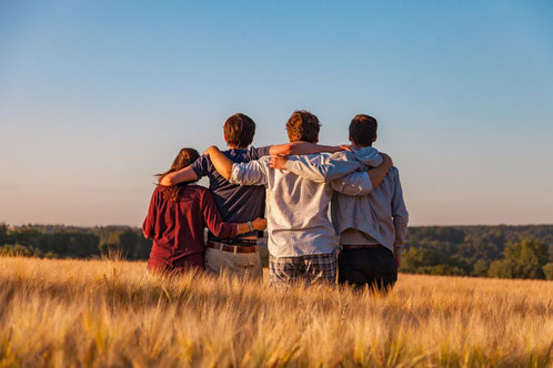 Groupe de jeunes unis dans un champ au coucher du soleil, symbolisant l’accompagnement des adolescents et jeunes adultes en Vendée par Émeline Guilbaud, thérapeute en EFT et Fleurs de Bach.