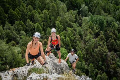 Aussicht von Belvédère de Nax auf das Rhonetal. Frau mit Kletterhelm und Klettergurt schaut auf das Rhonetal. 