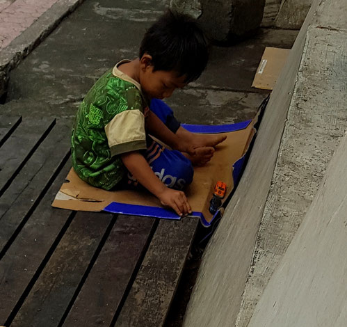 Ein kleiner Junge in Indonesien spielt am Straßenrand.