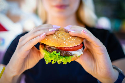 Junge Frau lässt sich einen Hamburger schmecken