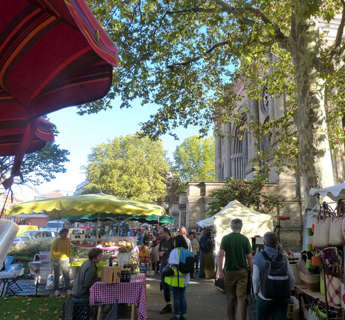 la photo représente plein de parasols rouges à rayures et des étals de forains 
