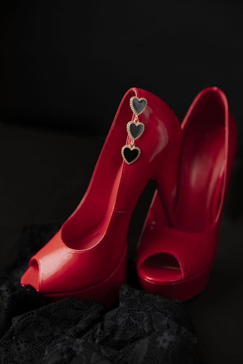 Rote High Heels mit daran befestigten Herzohrringen als stilvoller, femininer Eyecatche
