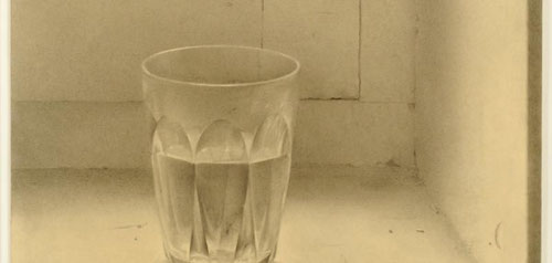 Isabel Quintanilla,Vaso1969.Lápiz sobre papel,34x25cm.Galería de Berlín,Hamburgo.Sencillez franciscana de un vaso de agua Duralex encajado en alfeizar,jamba, bisagra.La luz atraviesa el vaso y se refracta en todas sus facetas.Maestría de bodegón monocroma