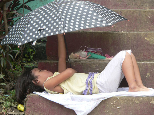 台風で増水する川沿いの小屋から避難して石段で休む少女　ケソン市で