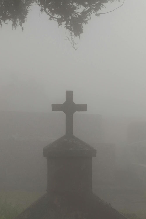 Ein Grabstein mit Kreuz im Nebel. Foto von Thgusstavo Santana auf Pexels.