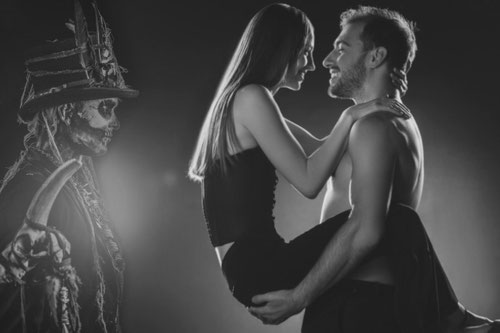 voodoo liebesritual verliebtes paar mit baron samedi im hintergrund