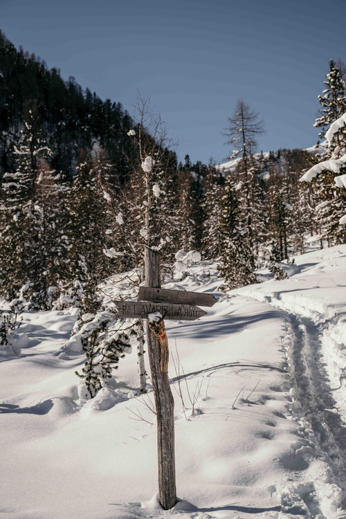 Winterlicher Wegweiser im Naturpark Fanes-Sennes-Prags; Schneeschuh- und Skitourengeher folgen dem präparierten Wanderweg durch verschneite Landschaft. ©Marika Unterladstätter
