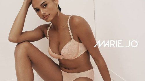 Model mit Marie Jo Avero BH und Rioslip gekleidet liegend sitzend mit Sportschuhen vor weißem Hintergrund.
