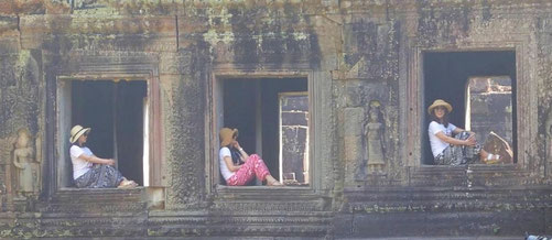 Bild: Drei Frauen ruhen sich in den Fenstern eines Tempels in Angkor Watt aus. 