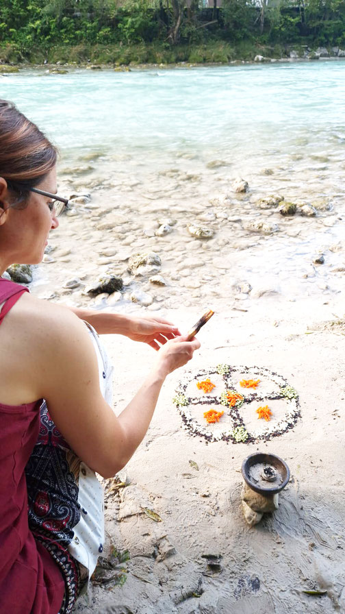 wunderschön dargelegtes Mandala aus Naturmaterialien am Flussufer; Kristina Kragh räuchert, um die Energie zu erhöhen