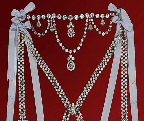 An opulent diamond-studded ceremonial adornment with cascading strands, teardrop-shaped gems, and silver ribbons tied in bows.