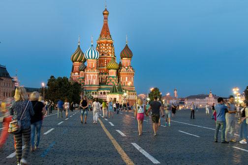 People walk across Red Square at dusk with St. Basil’s Cathedral brightly lit in the background.