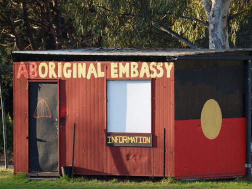 A small red building labeled "Aboriginal Embassy" displays the Aboriginal flag and an information sign on its front.