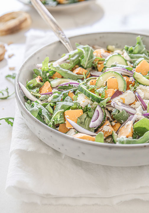 Herbstlicher Süßkartoffel-Rucola-Salat mit Feta und Balsamico-Dressing auf einem Teller serviert
