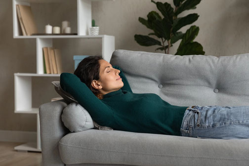 Hochsensible Frau nimmt sich bewusst eine Ruhepause auf der Couch