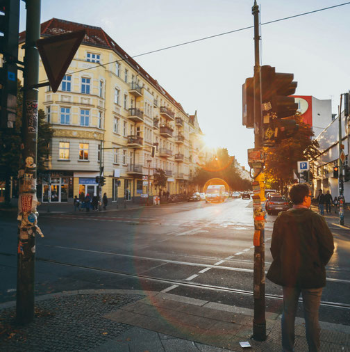 Mensch steht an einer Stadtstraße im warmen Abendlicht. 