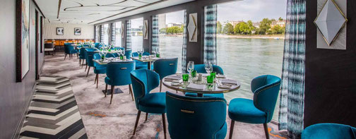 Elegantes Bordrestaurant eines Flusskreuzfahrtschiffes mit Panoramafenstern und Blick auf die Flusslandschaft