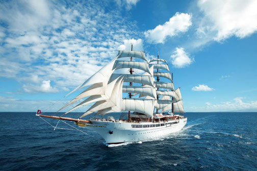 Großsegler der Sea Cloud Cruises mit vollen Segeln auf offenem Meer unter blauem Himmel.