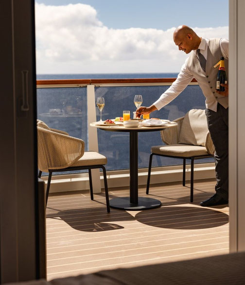 Ein Angestellter bringt ein Getränk auf eine Suite auf der Explora II