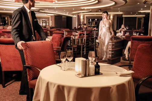 Kellner rückt Stuhl für Gast im Restaurant auf Silversea Kreuzfahrtschiff zurecht