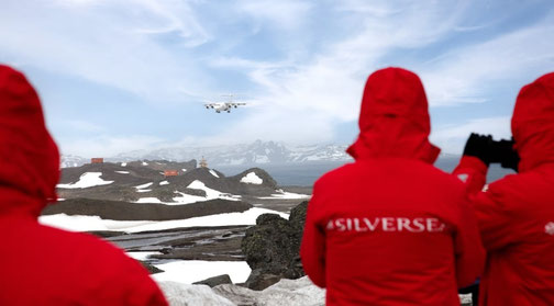 Silversea Fly and Cruise menschen mit roten Jacken die auf ein Flugzeug gucken