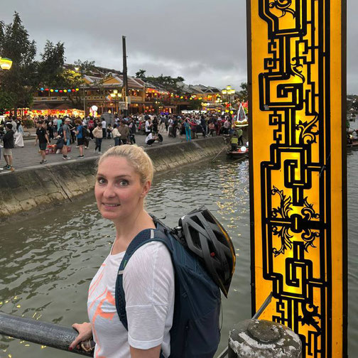 Anne Fischer von Emocean Cruises steht am Flussufer in einer asiatischen Stadt bei Abendstimmung während einer Reise mit der MS Europa 2 von Hapag-Lloyd Cruises.