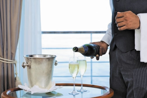 Ein Butler schenkt ein Glas Champagner ein