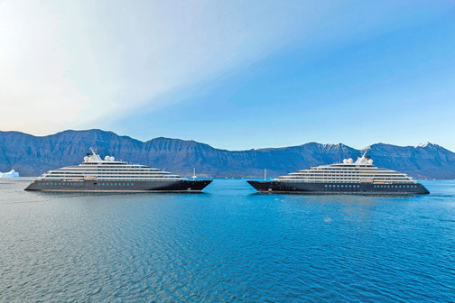 Yacht Expeditionsschiffe, die sich auf dem Meer gegenüberstehen mit Berglandschaft im Hintergrund