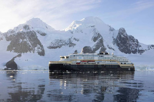 MS FRIDTJOF NANSEN fährt durch eisbedecktes Polarmeer vor verschneiten Bergen