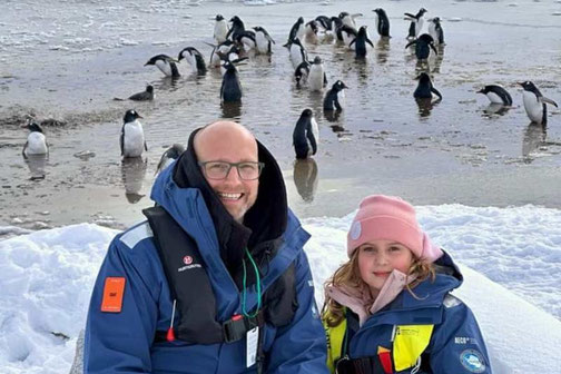 Vater und Tochter vor Pinguinen in der Antarktis