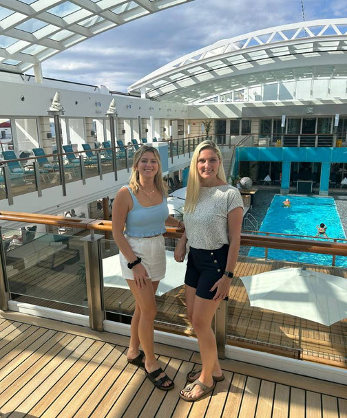 Anne Fischer und Nadine Erber von Emocean Cruises an Bord der EUROPA 2 auf dem Sonnendeck mit Pool im Hintergrund.