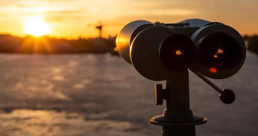 Fernglas, das auf den Sonnenuntergang über Wasser gerichtet ist
