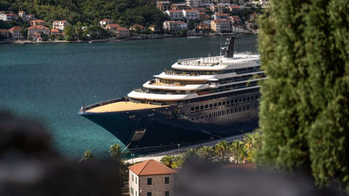 Luxuskreuzfahrtschiff im Hafen einer mediterranen Küstenstadt mit Blick auf die Bucht und historische Uferpromenade