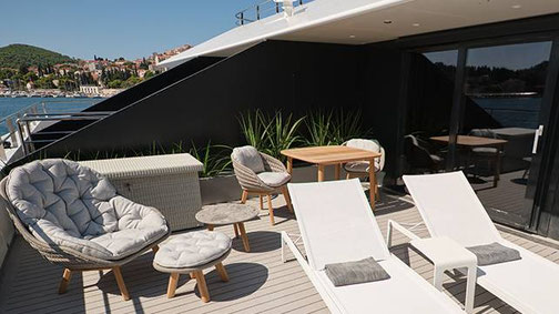 Große private Terrasse der Yacht Suite auf der Superyacht Emerald Kaia mit Sonnenliegen, Lounge-Möbeln und Meerblick.
