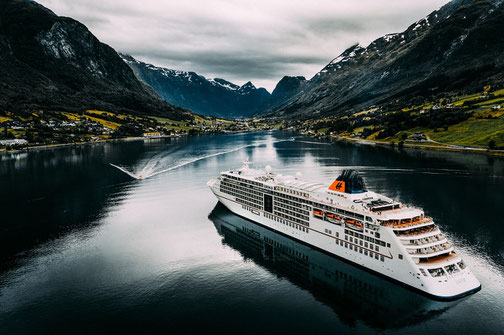 MS Europa 2 - Fahrt in die Fjorde umrahmt von grünen und teils schneebedeckten Berghängen