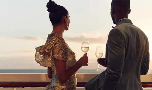 Paar steht mit Champagnergläsern an der Reeling von Crystal Cruises Schiff
