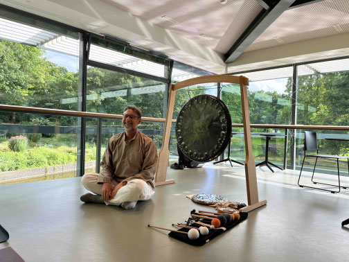 Martin Schmitz sitzt vor seinem Gong im Teehaus in Hamburg und sieht glücklich aus