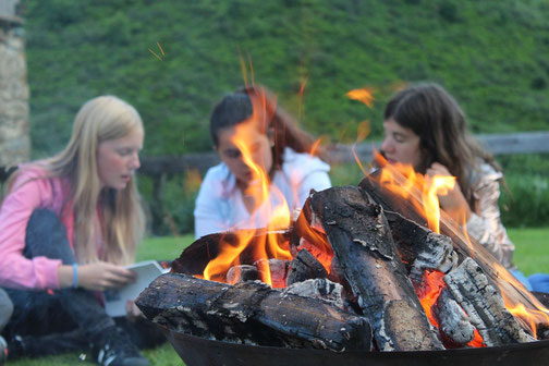 Gruppe singt am Lagerfeuer während ihrer Landschulwoche mit Erlebnisfahrten