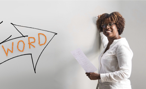 EIne junge Frau erklärt etwas an einer Whiteboard. Links ist ein groß aufgemalter schwarzer Pfeil zu sehen, in dem und dicker orangefarbener Schrift das Wort „Words“ steht.