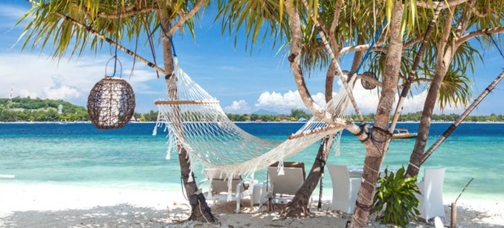 Hängematte an einem paradiesischen Sandstrand am türkisblauen Meer.