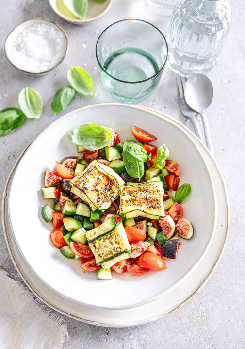 Gebratene Zucchini-Feta-Taschen auf mediterranem Salat mit Gurke, Kirschtomaten, Feige und Basilikum, verfeinert mit Olivenöl-Balsamico-Dressing.