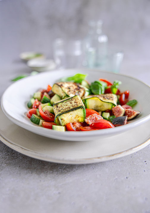 Gebratene Zucchini-Feta-Taschen auf mediterranem Salat mit Gurke, Kirschtomaten, Feige und Basilikum, verfeinert mit Olivenöl-Balsamico-Dressing.