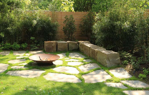 Feuerstelle mit Steinplatten, einer Sitzecke aus Grauwacke-Steinblöcken und Stahl-Feuerschale