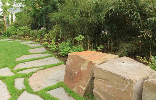 Natürlich angelegter Gartenweg mit Trittplatten aus Natursteinen grenzt an die Sitzblöcke an