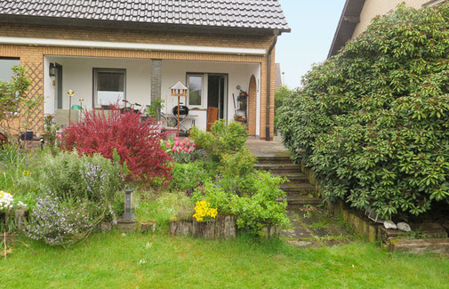 Vom Garten führen fünf schmale Stufen auf die Terrasse zum Haus
